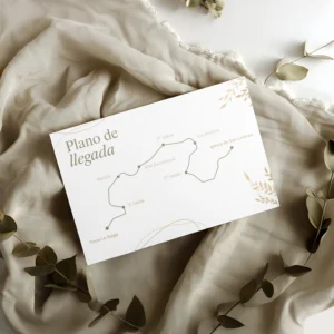 Plano de llegada para boda con diseño elegante en tonos beige y blancos, impreso sobre papel texturizado y acompañado de decoración con tela suave y ramas secas.