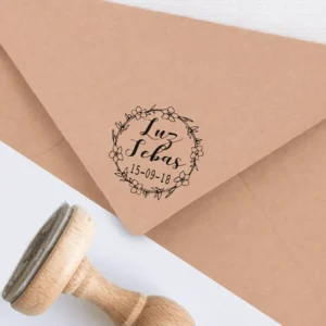 Sello personalizado para bodas con diseño floral, estampado en un sobre kraft. Incluye los nombres 'Luz y Sebas' y la fecha del evento, rodeados de una corona de flores