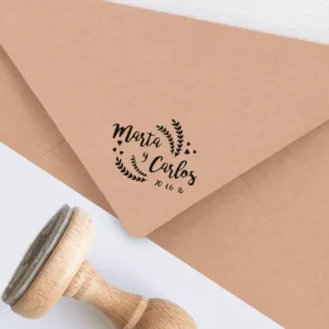 Sello personalizado para bodas con diseño rústico, estampado en un sobre kraft. Incluye los nombres 'Marta y Carlos' y la fecha del evento, decorado con detalles de hojas.