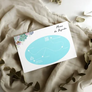 Plano de llegada para boda con fondo azul y detalles de suculentas en tonos pastel, estilo moderno y desenfadado, impreso en papel texturizado y acompañado de tela beige con hojas decorativas.